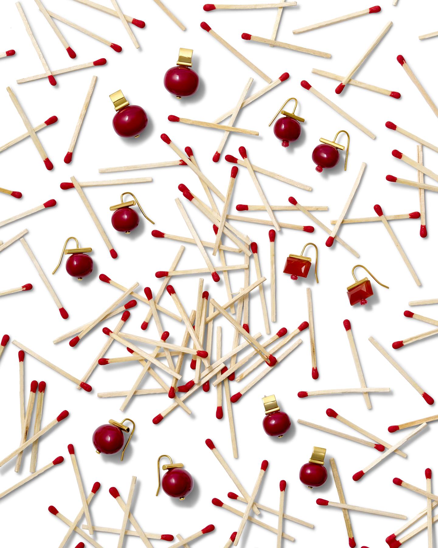 Red Pebble Pearl earrings and red stone earrings scattered among red-tipped matches