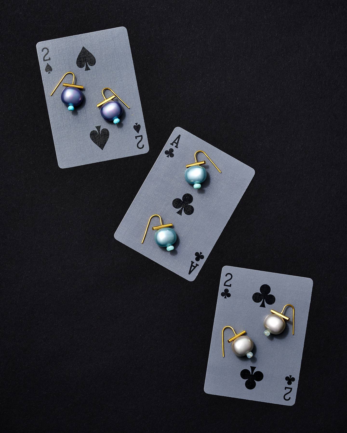 Pebble Pearl earrings in iris, aqua and silver on playing cards against black