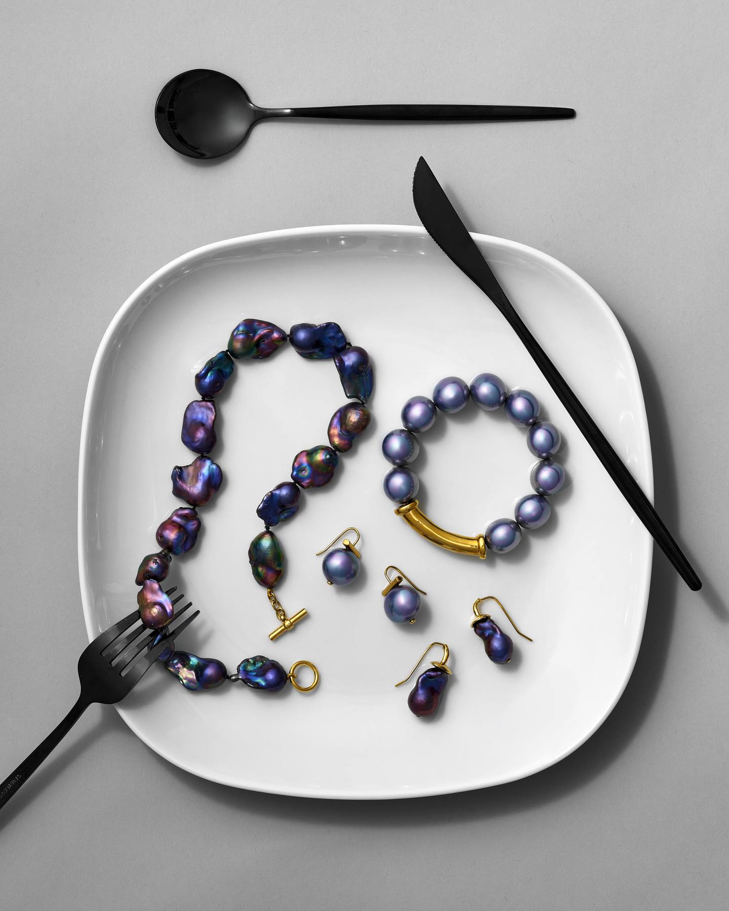Iris and black baroque Pebble Pearl jewelry served on a white plate with black cutlery